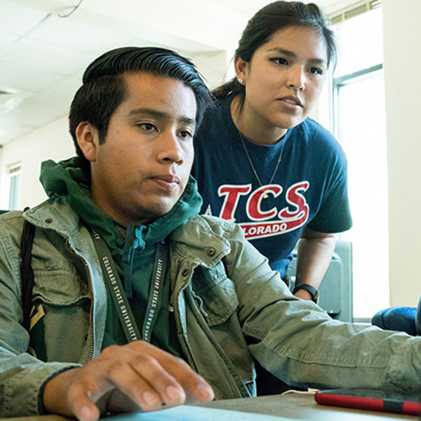 Native American student and instructor viewing a laptop screen
