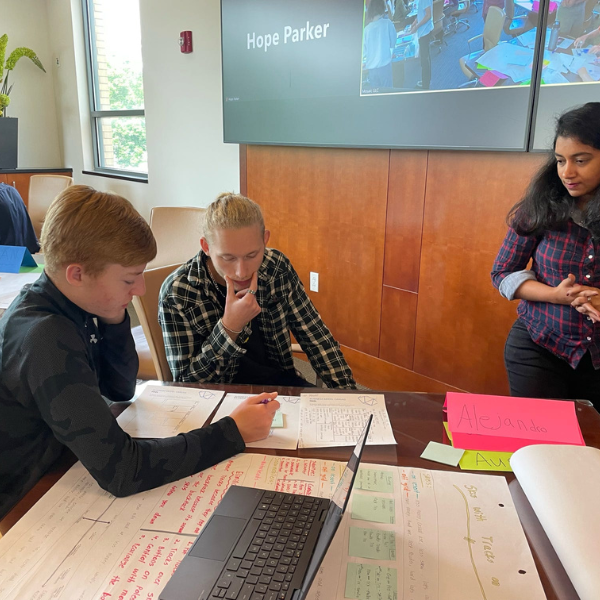 Two student and a teach collaborate to solve a problem during the Venture Validator summer program at Colorado State University.